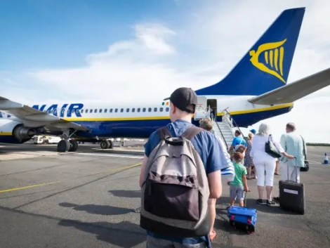 ÚVOD 15 Cestujúci s batohom kráča po odbavovacej ploche k lietadlu Ryanair, v pozadí ďalší pasažieri s batožinou