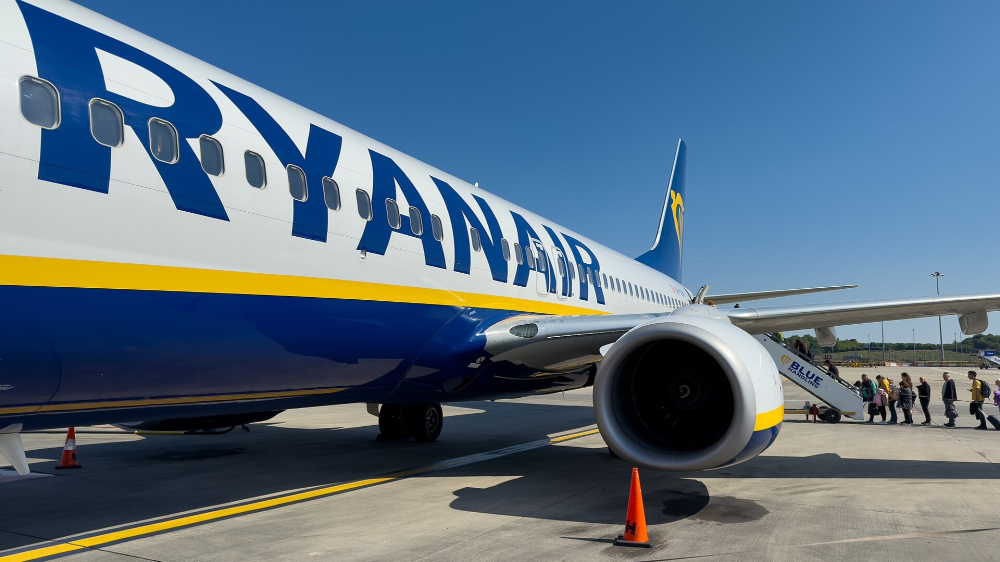 Boeing 737 v modro-žltých farbách Ryanairu, cestujúci nastupujú po schodoch na palubu