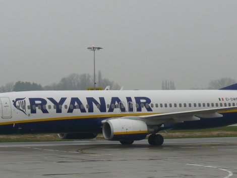 Boeing 737-800 v modro-žltých farbách Ryanairu roluje po mokrej odbavovacej ploche letiska pod zamračenou oblohou